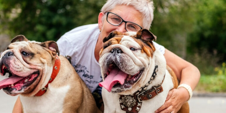 Elderly Woman Hugging Two Happy Bulldogs in Independent Living